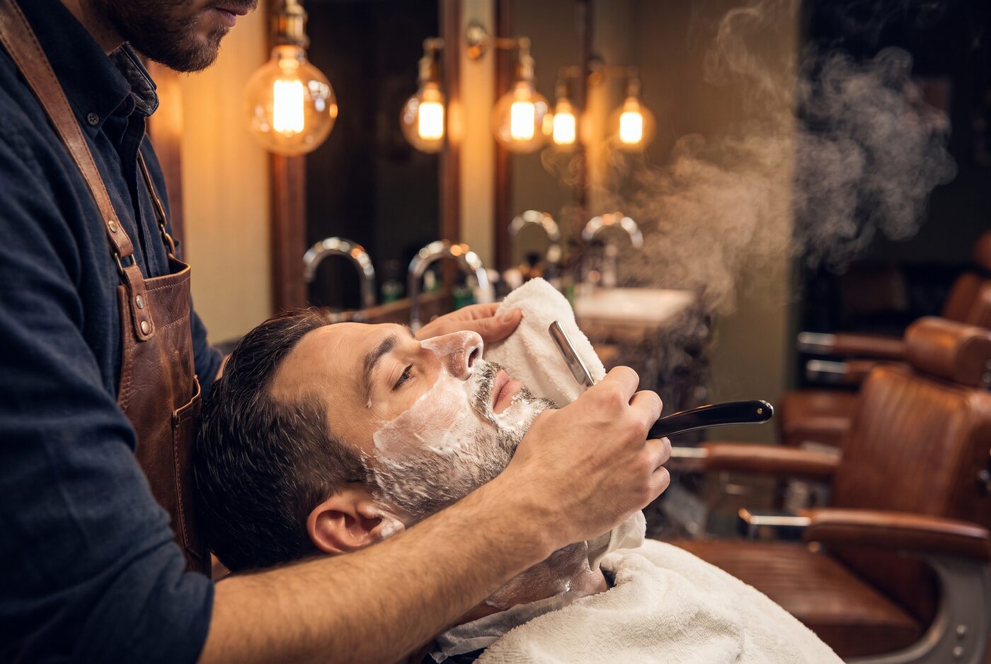 Barbier bei der klassischen Rasur mit heissem Tuch und Rasiermesser