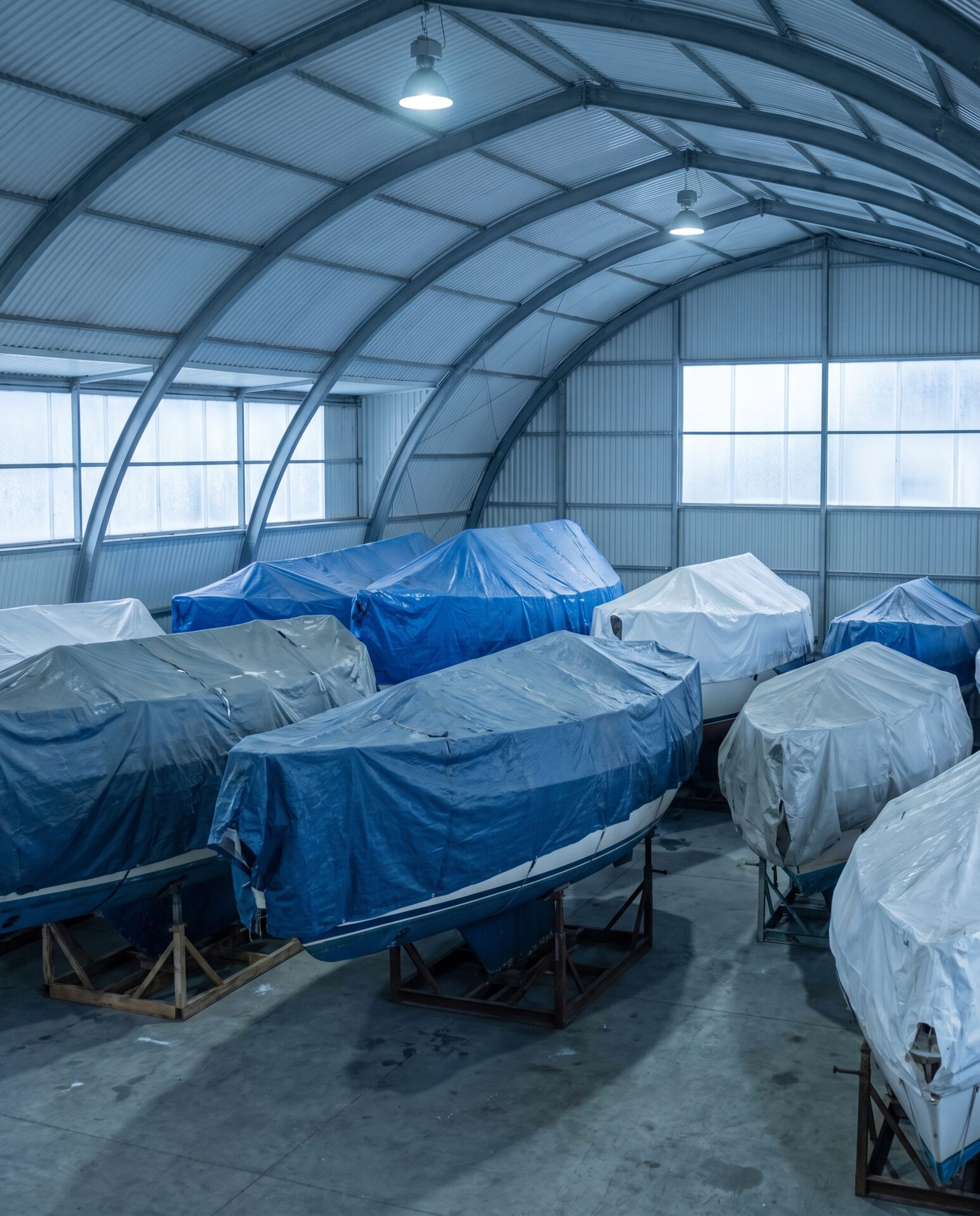 Winterlagerhalle mit abgedeckten Bootsrümpfen auf Böcken