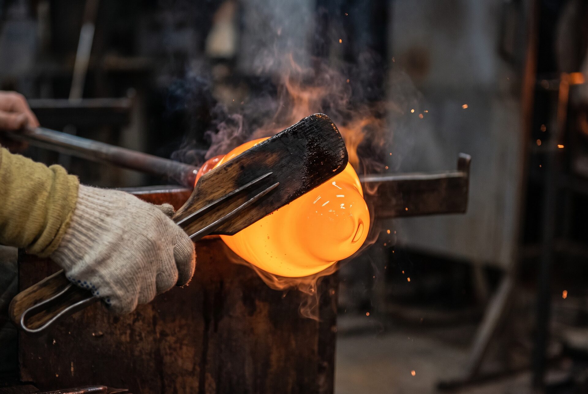 Nahaufnahme von geschmolzenem Glas, das mit Holzwerkzeug geformt wird
