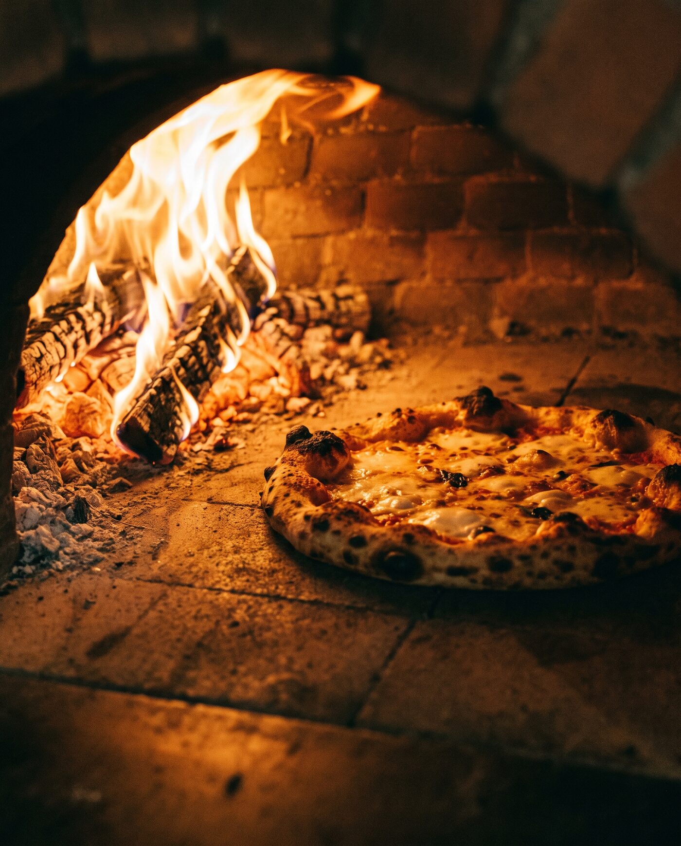 Pizza im lodernden Holzofen mit Flammen und warmem Glühen