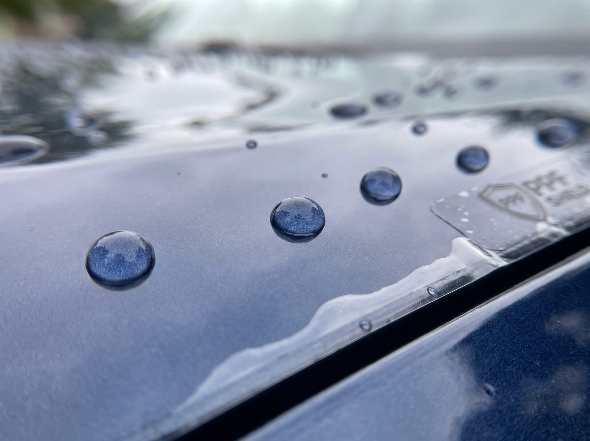 Makroaufnahme von Wassertropfen, die auf lackschutzfolierter Oberfläche perlen