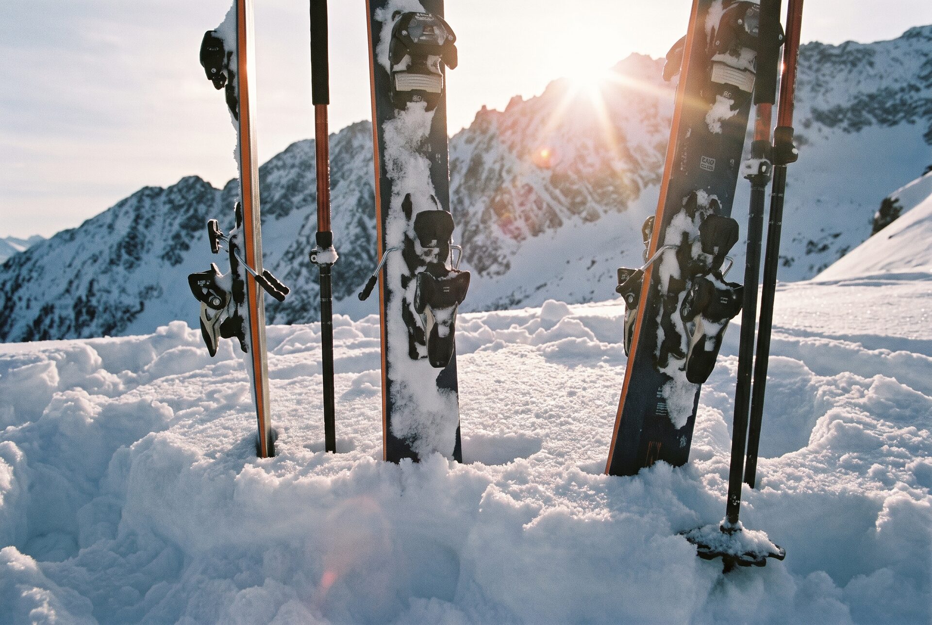Ski und Stöcke im Tiefschnee mit Sonne über einem Bergkamm