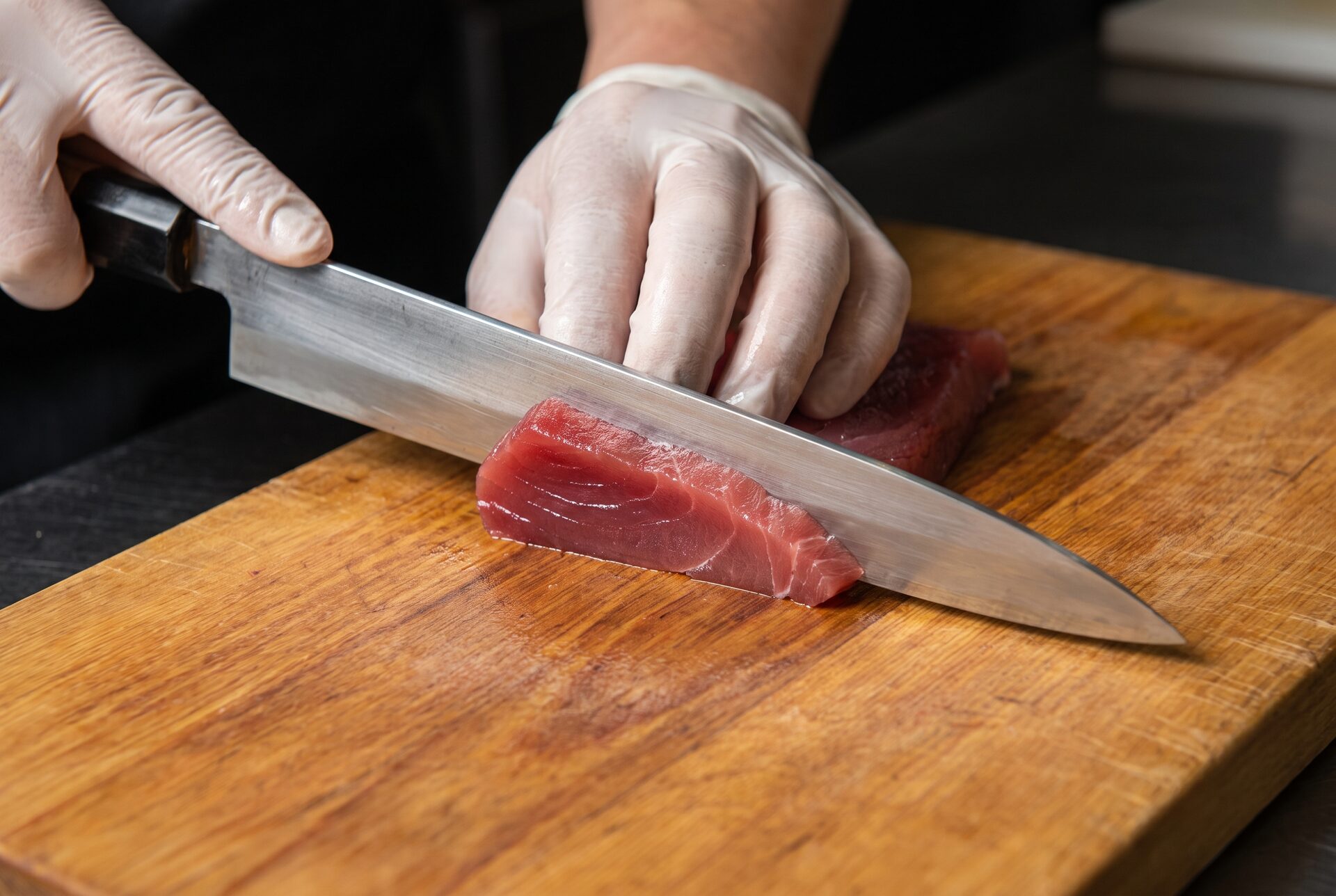 Sushi-Messer schneidet frischen Thunfisch auf einem Holzbrett