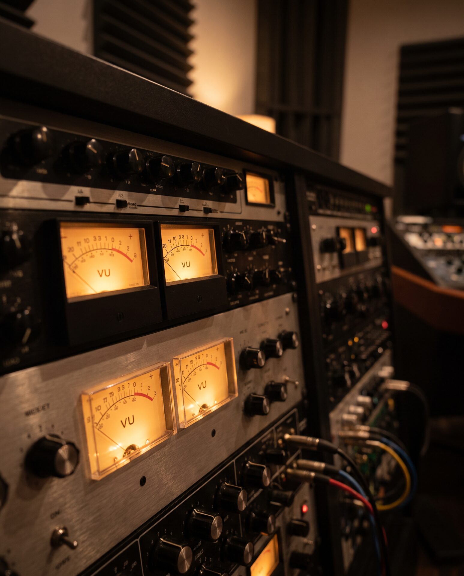 Rack mit analogem Outboard-Equipment und leuchtenden VU-Metern