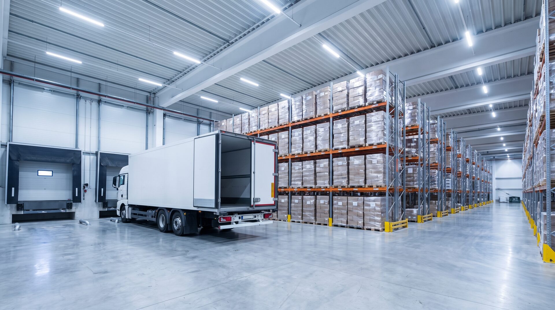FRACHTGUT – saubere Logistikhalle mit Paletten und Lastwagen an der Rampe